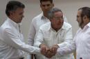 In this Wednesday, Sept. 23, 2015 photo, Cuba's President Raul Castro, center, encourages Colombian President Juan Manuel Santos, left, and Commander the Revolutionary Armed Forces of Colombia or FARC, Timoleon Jimenez to shake hands, in Havana, Cuba. In a joint statement, Santos and the FARC said they have overcome the last significant obstacle to a peace deal by settling on a formula to compensate victims and punish belligerents for human rights abuses. (AP Photo/Desmond Boylan)