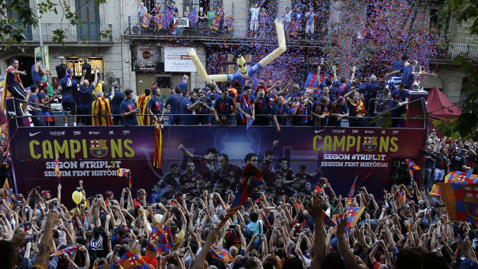 Fans cheers as FC Barcelona players ride on the team bus during celebrations in Barcelona, Spain Sunday June 7, 2015 after winning the Champions League final soccer match Saturday by beating Juventus Turin 3-1. Barcelona won the triple this season winning the Spanish League title, the Copa del Rey and the Champions League. (AP Photo/Emilio Morenatti)