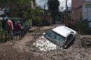 A car lays buried in mud after flooding triggered by Tropical Storm Manuel as residents try to clean up their neighborhood in Chilpancingo, Mexico, Thursday, Sept. 19, 2013. Manuel, the same storm that devastated Acapulco, gained hurricane force and rolled into the northern state of Sinaloa on Thursday before starting to weaken. (AP Photo/Alejandrino Gonzalez)