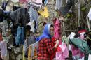 An Afghan woman collects her laundry from a tree in Piraeus, near Athens, Tuesday, March 8, 2016. European Union leaders hoped early Tuesday they reached the outlines for a possible deal with Ankara to return thousands of migrants to Turkey and said they were confident a full agreement could be reached at a summit next week. (AP Photo/Thanassis Stavrakis)