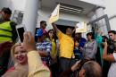 Newly elected opposition congressman Jorge Millan, center, holds up his credentials after receiving them from the National Electoral Council (CNE) in Caracas, Venezuela, Wednesday, Dec. 9, 2015. The Democratic Unity opposition coalition secured, by a single seat, a two-thirds supermajority, surpassing its even most-optimistic forecasts. (AP Photo/Fernando Llano)