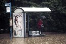 A woman shelters from the rain and the flodding at a bus stop, by standing on a bench, on a flooded highway linking Athens with its port of Piraeus, during a rainstorm on Friday, Feb. 22, 2013. Hours of heavy rainfall in Athens caused extensive flooding, inundating basements and forcing authorities to close major roads and a central subway station. The Greek fire brigade says it received more than 900 calls to pump out water in the greater Athens region Friday. (AP Photo/Petros Giannakouris)