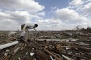 In this March 3, 2012 file photo, Jackson Hambree cleans up debris after a tornado struck in Marysville, Ind. Aiming to get people to safety sooner as a big storm approaches, the National Weather Service will expand that re-tooled severe weather warning system, from Kansas and Missouri to 12 more Midwestern states. Starting Monday, April 1, 2013, it will provide media outlets and emergency services with more detail about the strength of a brewing tornado or thunderstorm, what it may hit and when. (AP Photo/Nam Y. Huh)