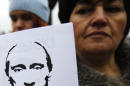 A woman holds a banner that reads: "Putin is Occupier" during a rally against the breakup of the country in Simferopol, Crimea, Ukraine, Tuesday, March 11, 2014. The Crimean parliament voted Tuesday that the Black Sea peninsula will declare itself an independent state if its residents agree to split off from Ukraine and join Russia in a referendum. Crimea's regional legislature on Tuesday adopted a "declaration of independence of the Autonomous Republic of Crimea." The document specified that Crimea will become an independent state if its residents vote on Sunday in favor of joining Russia in the referendum. (AP Photo/Darko Vojinovic)