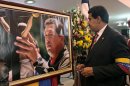 FILE - In this March 8, 2013 file photo released by Miraflores Press Office, Venezuela's acting President Nicolas Maduro stands in front of a portrait of Venezuela's late President Hugo Chavez after a symbolic swearing in ceremony in the presence of the flag-draped coffin of Chavez at the military academy where the funeral ceremony was held earlier in Caracas, Venezuela. For his loyal followers, Chavez was already a living legend on par with independence era hero Simon Bolivar even before his March 5 death from cancer. In a mere three weeks, however, Chavez has ascended to divine status, at least according to political rhetoric, as the government and his die-hard loyalists build a religious mythology around him ahead of April 14 elections scheduled to pick a new leader. (AP Photo/Miraflores Press Office, File)