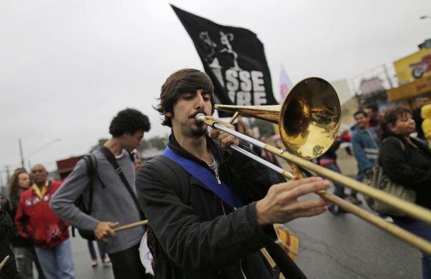 A man plays a trombone during a protest in the Capao Redondo neighborhood of Sao Paulo, Brazil, Tuesday, June 25, 2013. Protesters on Tuesday returned to the streets in low-income suburbs of Brazil's biggest city to demand better education, transport and health services, one day after President Dilma Rousseff proposed a wide range of actions to reform Brazil's political system and services. (AP Photo/Nelson Antoine)