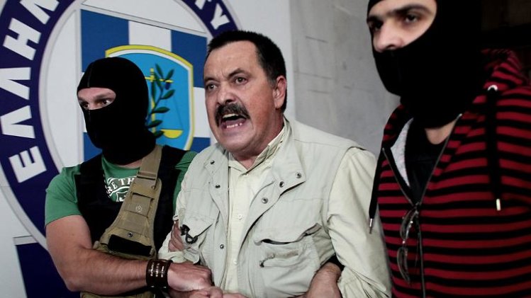 Christos Pappas, lawmaker of the extreme far-right Golden Dawn party, is escorted by masked police officers to the prosecutor's office from police headquarters in Athens on September 29, 2013