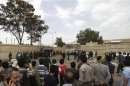 People gather in front of the gates of the police academy where a suicide bomb attack took place in Sanaa