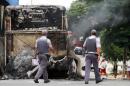 Policemen pass by a burnt bus at Vida Nova bus station, in Campinas, some 96 km from Sao Paulo, Brazil on January 13, 2013
