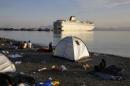 Syrian refugees camp on a beach by the of the port of Kos as the passenger ship "Eleftherios Venizelos" is docked