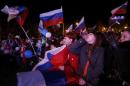 People celebrate and wave Russian flags as the preliminary results of today's referendum are announced in the Crimean city of Sevastopol