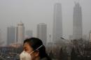 A woman wearing a protective mask makes her way in a business district on a heavily polluted day in Beijing