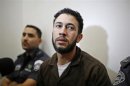 Palestinian Abu Rida sits next to Israeli prison guards before his indictment at the district court in Beersheba