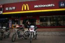 A woman walks past electric bikes sitting outside a McDonalds fast-food outlet in central Beijing
