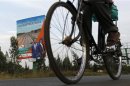 A man cycles past a campaign poster by Kenya's PM and presidential candidate Odinga in Kisumu