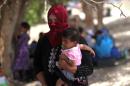 A displaced Iraqi woman who fled the al-Falahat village west of Fallujah holds a child as they wait to receive food and aid at the village of al-Azraqiyah, on June 4, 2016
