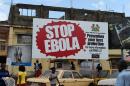 People walk past an Ebola prevention billboard in Freetown, on November 7, 2014