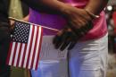 A woman holds U.S. flag during the oath of allegiance to the United States during a naturalization ceremony in New York
