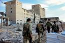 Syrian army soldiers patrol near a building previously used for storing seeds in Deir Hafer, a former Syrian bastion of the Islamic State group, on December 2, 2015