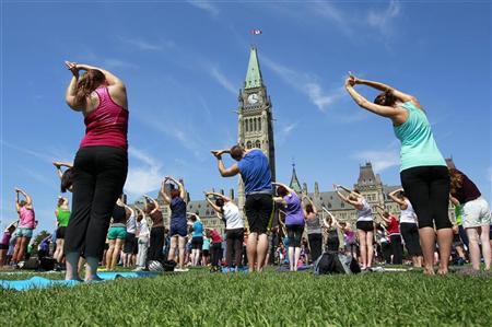 People take part in a free weekly yoga class on the front lawn of Parliament Hill in Ottawa