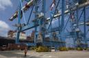 A worker walks near cranes unloading containers from a ship at the port of the northern city of Haifa