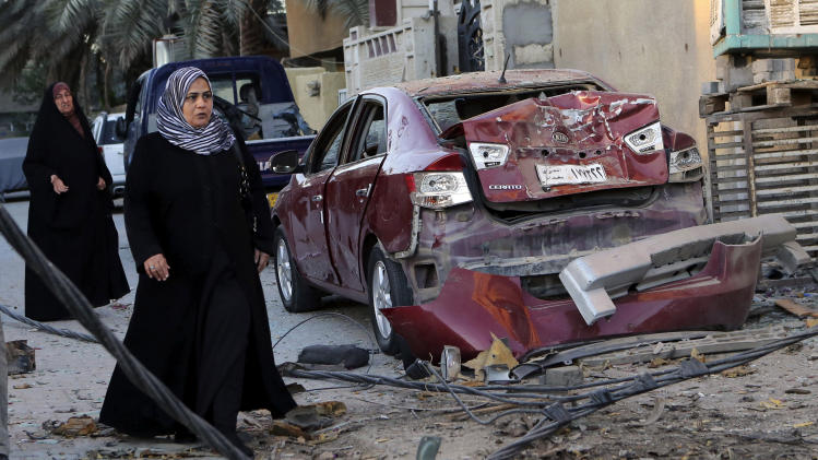 FILE - In this Oct. 8, 2013 file photo, women walk past the aftermath of a car bomb attack in the mainly Shiite neighborhood of Zafaraniyah in southeastern Baghdad, Iraq. Al-Qaida has come roaring back in Iraq since U.S. troops left in late 2011 and now looks stronger than it has in years. The terror group is capable of carrying out mass-casualty attacks several times a month, driving the death toll in Iraq to the highest level in half a decade. It sees each attack as a way to maintain an atmosphere of chaos that weakens the Shiite-led government’s authority. (AP Photo/Hadi Mizban, File)