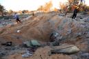 Libyans stand next to a crater and debris at the site of a jihadist training camp, targeted in a US air strike, near the Libyan city of Sabratha on February 19, 2016