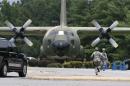 Security personnel run past a C-130 aircraft on static display at the front gate of Little Rock Air Force Base in Jacksonville, Ark., Wednesday, July 23, 2014. The base has been on lockdown since late morning Wednesday. (AP Photo/Danny Johnston)