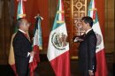 Mexico's outgoing President Calderon holds the national flag as new President Pena Nieto salutes during a handover ceremony at the Palacio Nacional