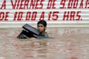 A young man carrying a stolen computer wades through a flooded street in Acapulco on September 16, 2013