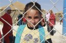 A Syrian refugee girl looks out from behind a fence as she attends school at the Zaatari refugee camp in Mafraq