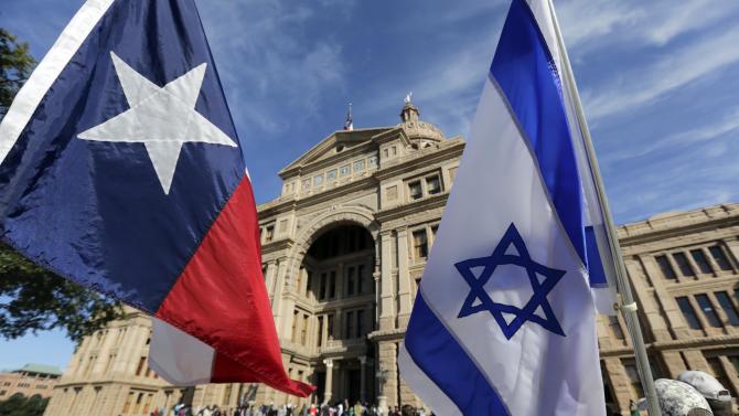 The Texas and Israeli flags are waved by protesters who gathered to disrupt and heckle a group gathered for a Texas Muslim Capitol Day rally, Thursday, Jan. 29, 2015, in Austin, Texas. Hundreds of Muslims gathered for the rally as part of their biennial Texas Capitol lobbying day. (AP Photo/Eric Gay)