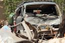 Iraqi security forces inspect a destroyed car at the site of an explosion in Baghdad on April 9, 2014