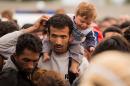 Migrants queue up for buses after they arrived at the border between Austria and Hungary near Heiligenkreuz, about 180 kms (110 miles) south of Vienna, Austria, Saturday, Sept. 19, 2015. Thousands of migrants who had been stuck for days in southeastern Europe started arriving in Austria early Saturday after Hungary escorted them to the border. (AP Photo/Christian Bruna)