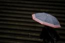 A tourist carries an unmbrella during a rain storm on Wall St. in New York's financial district