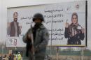A policeman stands near a billboard for the presidential election at a checkpoint in Kabul