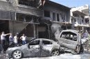 People gather around wreckage after a car bomb exploded in the Jaramana district of southeast Damascus
