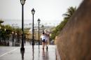 Two women walk with the protection of an umbrella in Old San Juan, Puerto Rico, Saturday, Aug. 2, 2014. Bertha pushed just south of Puerto Rico on Saturday as it unleashed heavy rains and strong winds across the region. (AP Photo/Ricardo Arduengo)