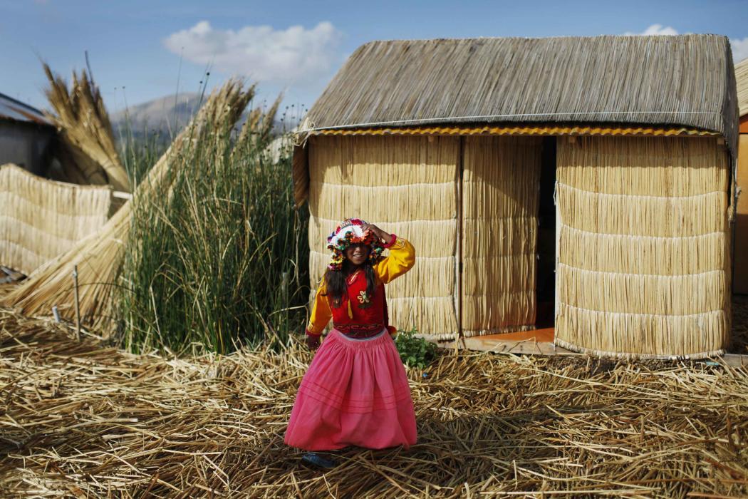 An Andean girl walks in front of her home, a straw hut, at a Uros island at Lake Titicaca in Puno