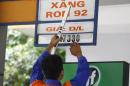 An employee changes a price sign at a petrol station in Hanoi