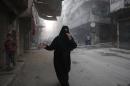 A woman runs in a street in Aleppo, following a reported barrel bomb attack by Syrian government forces on May 30, 2015
