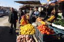 Iraqis walk past an open air market in the center of the city of Fallujah, west of the capital Baghdad on January 8, 2014, following days of fighting between Iraqi security forces and militants