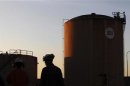 A worker is silhouetted as he walks past fuel storage tanks at an oil refinery in Melbourne
