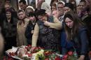 The mother of Sigarov Alexander, 24, reaches for his body at a church during the funeral for three people killed last Sunday in a shooting by unknown gunmen at a checkpoint, in Slovyansk, Ukraine, Tuesday, April 22, 2014. (AP Photo/Manu Brabo)