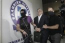 Far-right Golden Dawn party leader Mihaloliakos is escorted by anti-terrorism police officers as he leaves the Greek police headquarters in Athens