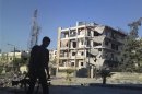 A member of the Free Syrian Army walks near a damaged building in Aleppo