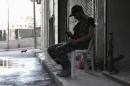 A Free Syrian Army fighter sits on a chair as he uses his mobile phone in Ashrafieh, Aleppo