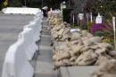 A man places sandbags at the top of a street lined with K-rail and sandbags in Glendora, Calif., as the city and residents prepare for possible flooding Thursday, Feb. 27, 2014. The first wave of a powerful Pacific storm spread rain and snow early Friday through much of California, where communities endangered by a wildfire just weeks ago now faced the threat of mud and debris flows. (AP Photo/Reed Saxon)