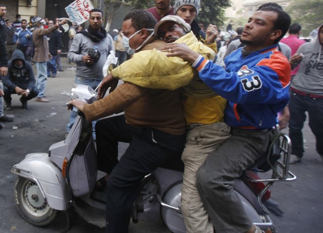 Protesters transport an injured man on a motorcycle during clashes against riot police near Tahrir Square in Cairo