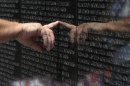 A visitor to the Vietnam Veteran's Memorial touches the name of a fallen soldier etched on the wall of the memorial in Washington, Friday, May 25, 2012. On Monday, the Vietnam Veterans Memorial Wall will begin the national commemoration of the Vietnam War's 50th anniversary. (AP Photo/Susan Walsh)